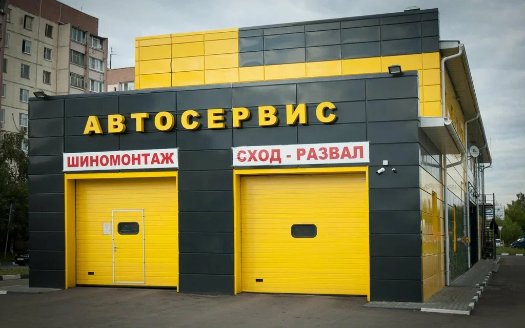 Название шиномонтажа над жёлтыми въездными воротами
