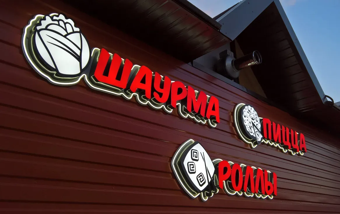 Красные световые названия на компактном фасаде шаурмичной