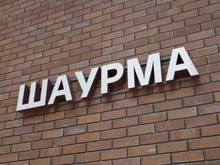 Белые буквы «Шаурма» на кирпичном фасаде