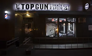 Белые световые буквы TOPGUN на тёмном фасаде