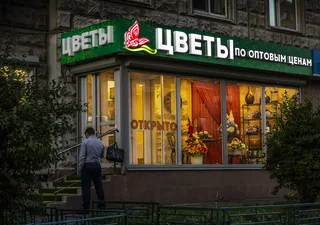 Белые световые буквы над витриной цветов вечером