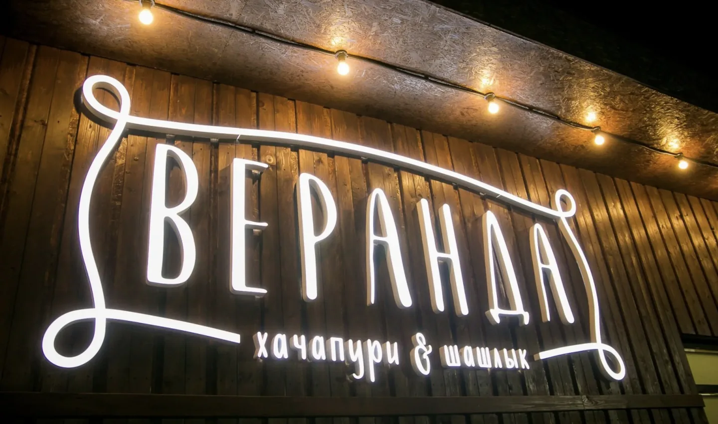 Световая надпись «Веранда» на деревянной стене
